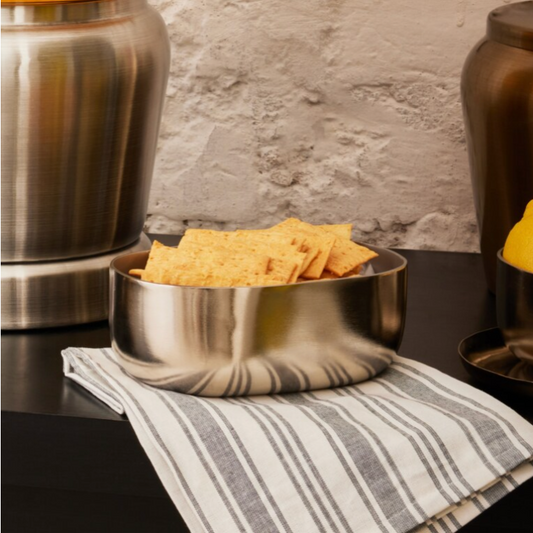 A Stainless Steel Celestique Bowl in a luxurious silver finish with crispy crackers placed inside